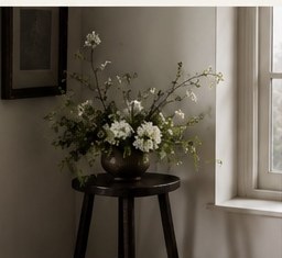 A quiet interior with a floral arrangement beside a window